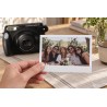 Tirage Instax Wide tenu en main devant un Wide 210 noir