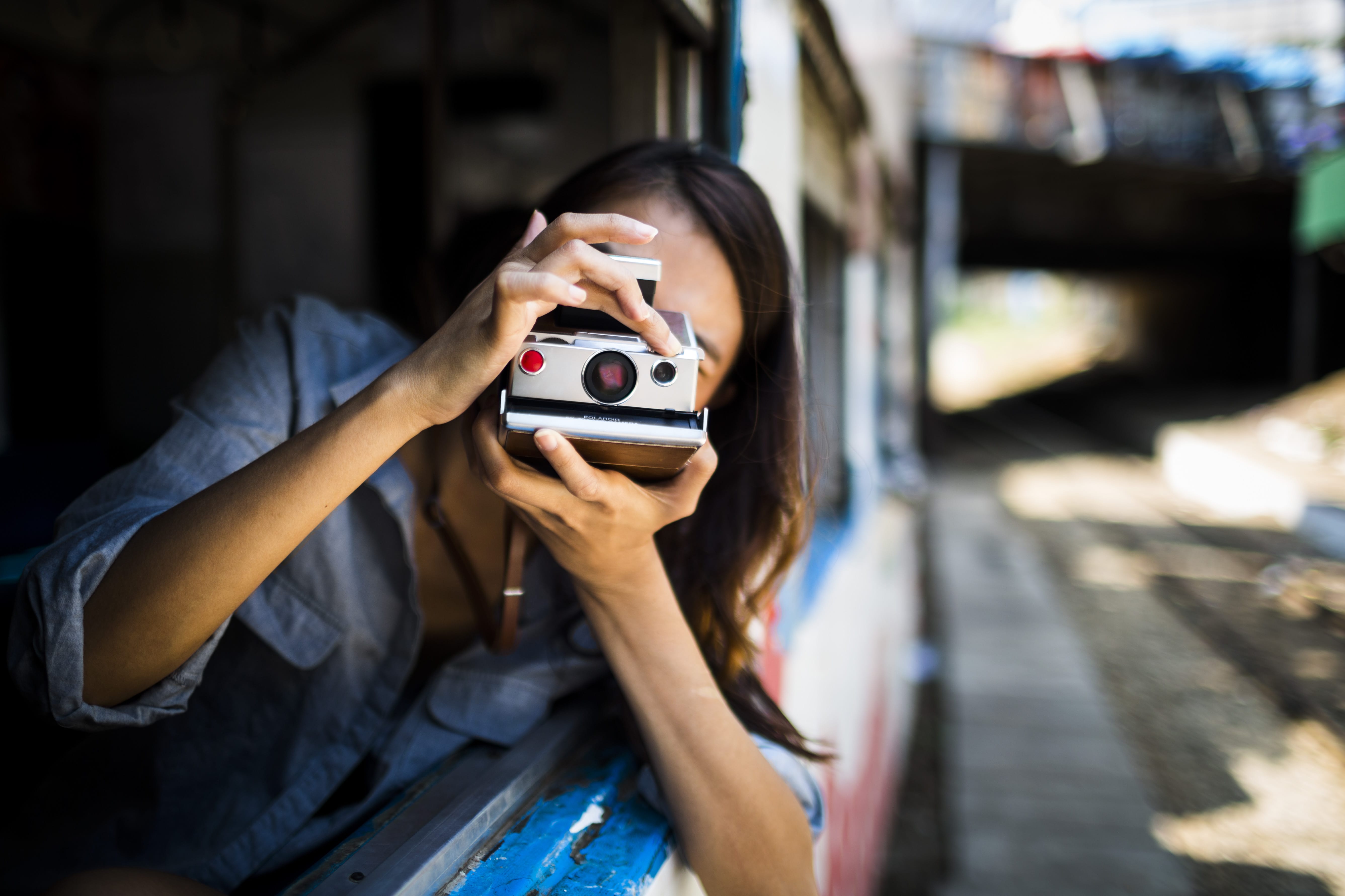 Femme voyageant prenant une photo avec un appareil polaroid depuis un train